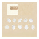 A beige card or packaging insert showing a set of white embossed or raised decorative frame shapes, including oval, scalloped, and shell-like motifs. A small cream textured label with a brown brand plaque appears in the upper left.