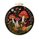 A circular embroidery hoop containing a detailed floral and mushroom embroidery design on black fabric, with a wooden hoop and white tension adjuster visible at the top, isolated on a white background.