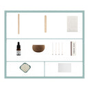 A product kit layout on a white background with a light blue border, showing multiple included items: two wooden sticks, a white cloth, a small amber dropper bottle, a brown bowl, four metal rods, a vertical box labeled 'ZOO HOME', a small dish of white powder, and a blank white square.