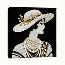 Decorative wall art of a woman wearing a beaded hat and jewelry on a black background