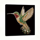 A square black canvas wall art print featuring a highly detailed, sparkling hummingbird embellished with gold, green, red, and white rhinestones, shown from a three-quarter angle against a white background.