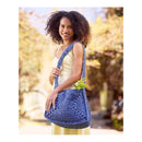 Woman holding a blue crocheted bag outdoors