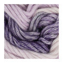 A close-up of soft, fuzzy yarn strands in a variegated blend of lavender purple, lilac, and pale blush pink.