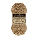 A skein of Scheepjes Stone Washed XL yarn in a warm tan-brown color, centered on a plain white background with its paper label visible.