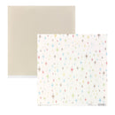A sheet of patterned paper with a white background and scattered multicolor starburst motifs, shown in front of a plain beige backing sheet on a white background.