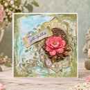A square handmade greeting card with a vintage-style ornate frame design, a pink peony flower, and a banner reading 'With Gratitude,' displayed on a rustic wooden surface with soft floral props in the background.