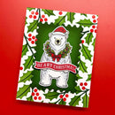A square Christmas greeting card featuring a white polar bear wearing a red Santa hat and green wreath with a red bow, centered on a dark green background with a red 'BEARY CHRISTMAS' banner. The card is framed by a white border with green holly leaves and red berries, shown against a solid red background.