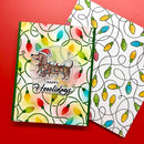A handmade greeting card and matching envelope featuring a dachshund wearing a Santa hat and holiday lights, displayed on a solid red background.