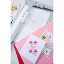 Holiday greeting cards with snowflake designs on a pink surface