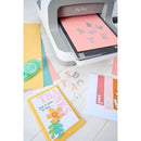 Card making setup with a cutting machine and handmade cards on a white surface