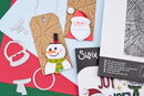 A styled flat-lay of Christmas-themed crafting supplies, including paper tags with a snowman and Santa design, metal die-cut shapes, and a package labeled 'Sizix' on a red, green, and white background.