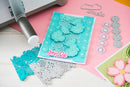 Card with decorative cutouts and a stamp on a pink surface