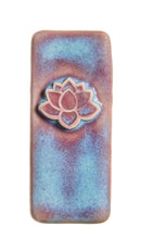 A rectangular ceramic tile with rounded corners, featuring a textured blue and brown glaze and a raised lotus flower motif in the center.