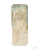 A rectangular cream-colored wax melt or solid wax block with a dripping design and an embossed lotus flower motif near the top, featuring subtle iridescent green and blue sheen on the upper section, set against a plain white background.