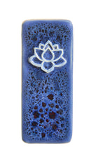 A rectangular ceramic tile with rounded corners, featuring a glossy dark blue and black speckled glaze and a white raised lotus flower design near the top center, shown on a plain white background.