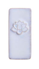 A rectangular ceramic tile with rounded corners, featuring a raised lotus flower motif in the center. The tile has a light lavender-blue glazed surface with subtle warm beige edging and a white lotus design.