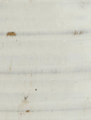 A close-up of a white textured surface with subtle horizontal ridges and a few small brown specks.
