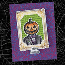 A handmade Halloween greeting card featuring a jack-o'-lantern-headed figure in a suit, framed by an ornate gold border on a purple damask-patterned cardstock, set against a black spiderweb background.