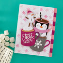 A handmade holiday greeting card featuring cartoon penguins and a snowman with hot cocoa cups, styled on a teal background with marshmallows and a ceramic mug.