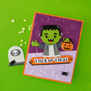 A handmade Halloween greeting card featuring a green Frankenstein character holding a jack-o'-lantern, with 'Trick or Treat' written on an orange banner. The card is styled on a bright green background with a small tombstone prop.