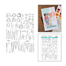 A sheet of black line-art temporary tattoo or stamp designs shown beside a sample card featuring an illustrated woman, with a watercolor palette and another printed sheet visible on a wooden surface.
