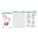 Three Spellbinders 'Mug and Cocoa' craft paper sheets shown on a white background: cutting dies with penguin and mug illustrations, a sheet of white snowflake stencils, and clear stamps with holiday phrases and swirl designs.