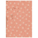 A rectangular sheet of textured pink paper with a repeating pattern of small white daisy-like flowers and a few scattered brown stain marks, shown against a white background.
