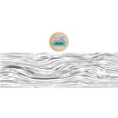 A small round wooden lid or coaster with a colorful label reading 'The Pine Tree Shop' and 'Moss Green' is shown above a long horizontal strip of gray wavy wood grain on a white background.