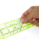 Hand holding a green ruler with black grid lines on a white background