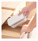 Hand picking up the white folded Universal Crafts Artlight pro out of a wooden cabinet draw.