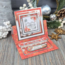 A handmade layered pop-up greeting card with a red and orange autumn leaf pattern, featuring a central black-and-white house illustration and seasonal text, displayed with holiday decorations on a rustic wood surface.