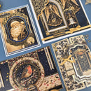 Four ornate Christmas-themed greeting cards arranged on a blue background, featuring gold and navy designs with a Santa portrait, angel, bell, robin, and decorative architectural borders.
