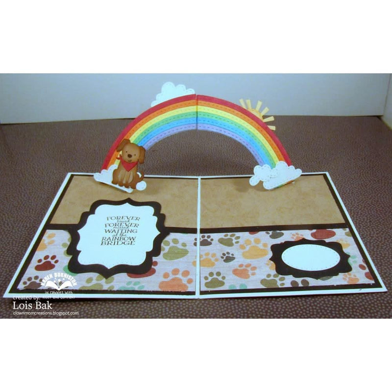 Pop-up card with a rainbow, bear, and paw prints on a brown surface.