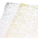 Two sheets of white patterned craft vinyl or contact paper with metallic foil accents, one in silver and one in gold, displayed diagonally on a white background.