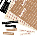 A flat lay of assorted rectangular paper message cards with printed phrases such as 'Happiness looks good,' 'Sending you hugs,' 'Just for you,' 'Thanks for being wonderful,' 'Just for you again,' 'Thinking of you,' 'A little thought for you,' and 'So proud of you.' The cards are shown in black, beige, and light brown tones on a white background.
