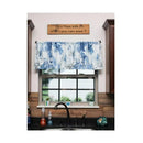 A kitchen window with a blue and white abstract patterned valance, shown in a real kitchen setting with a sink, cabinets, and a wooden sign above the window.