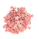 A pile of small, five-petal star-shaped flower embellishments in a dusty pink color, arranged on a solid white background.