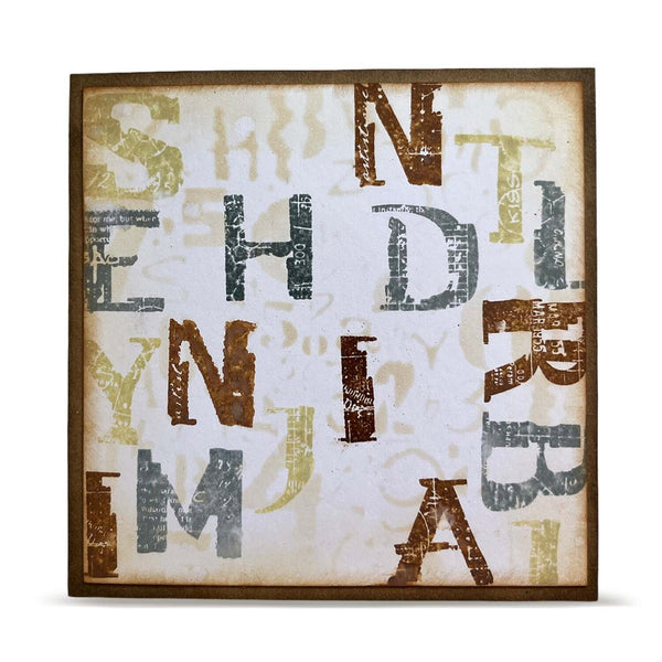 A square framed art print featuring distressed, stylized letters spelling out 'SHEILA' in brown, gray, and gold tones on a cream background with a dark brown frame.