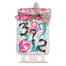 A decorative gift tag or sign with a pink lid, silver glitter ribbon bow, and colorful numbers on a white background.