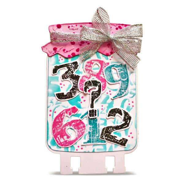 A decorative gift tag or sign with a pink lid, silver glitter ribbon bow, and colorful numbers on a white background.