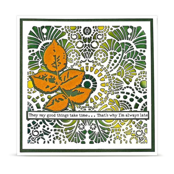 A square greeting card featuring a white background with a green border and an intricate green and yellow mandala-style pattern. A large orange leaf graphic is layered over the left-center of the design, and a white banner across the lower middle contains the text, 'They say good things take time.