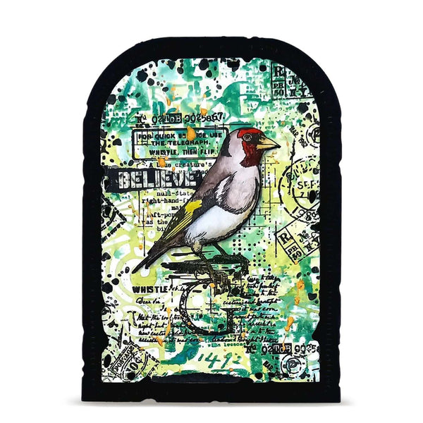 Arched decorative plaque featuring a mixed-media collage with a goldfinch bird, vintage stamps, handwritten notes, and abstract splatters in green, black, white, yellow, and red.
