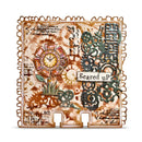 A square decorative mixed-media art piece featuring a distressed vintage aesthetic. The design includes a central clock motif, a stylized flower, green ornate gears, cursive script, and the words 'Scared up' on a white banner, all framed by a scalloped metallic-looking border on a white background.