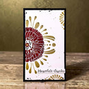 A handmade greeting card with a black border, featuring a large textured red and gold floral design on a white background with the text 'Heartfelt thanks' at the bottom, displayed on a wooden surface against a warm olive background.