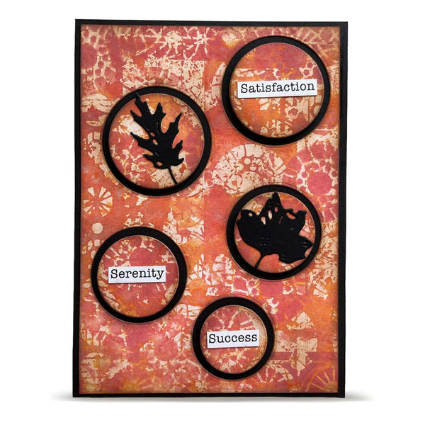 A square decorative card or art print with a distressed orange and pink patterned background, black circular frames, black leaf silhouettes, and small white labels reading Satisfaction, Serenity, and Success.