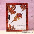 A handmade greeting card featuring autumn leaves with holes, set against a textured pink background. The card has a white center, a red and orange marbled border, and the printed text 'Celebrate the colours of the season'.