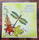 A handmade layered paper card featuring a detailed dragonfly, autumn leaves, and text reading 'Believe Be Strong Be True To You' on a yellow-green background.