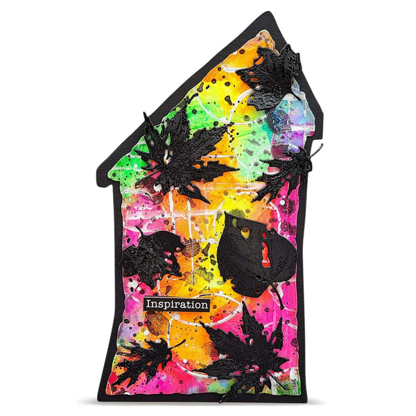 A house-shaped decorative plaque featuring a vibrant multicolor paint splatter background with black textured leaf overlays and a small black label reading 'Inspiration'.