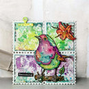 A decorative scrapbook or art card featuring a colorful bird layered over distressed postage stamp designs, with a flower, handwritten notes, and a small green clip at the top, photographed against a light textured wall.