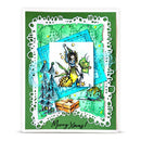 A handmade layered Christmas card featuring a green background, a white scalloped die-cut border, and multiple colorful graphic elements including a white central square with a whimsical elf illustration, blue and teal frames, a small gift box, and the text 'Merry Xmas!' at the bottom.